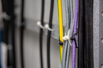 Cables fastened with white ties on the cable ladder. Black, gray, yellow, purple wires. Cable...