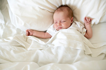 A Sweet newborn baby girl sleeping in white bed