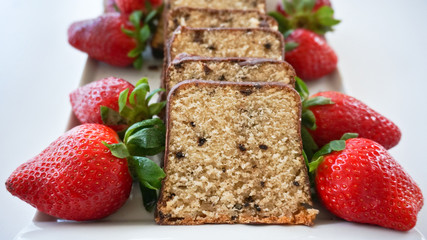 Sliced chocolate biscuit decorated with fresh ripe strawberries on white plate