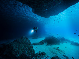 Seascape of coral reef in the Caribbean Sea / Curacao with Diver in cave 