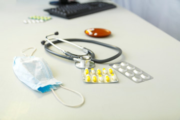 On a gray table is a medical mask, a stethoscope and medicines concept.