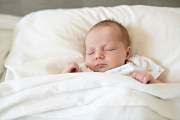 A Sweet newborn baby girl sleeping in white bed
