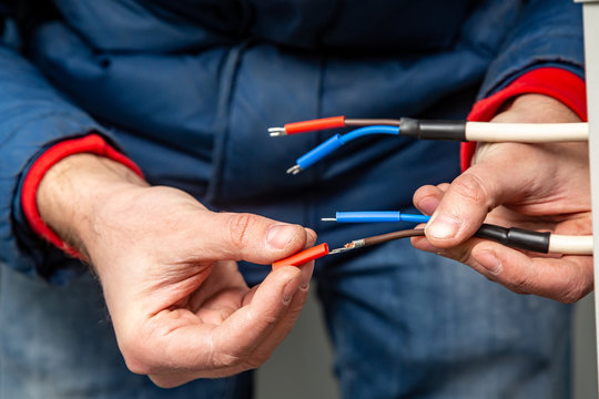 Hands putting insulation on wires. Red, blue, white.Close-up. Horizontal orientation. 
