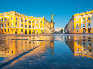 Odessa/Ukraine -05-06-2020: golden lights and reflections in blue water under sky of buildings and monument of city founder Duke in Odessa in Ukraine with copy space