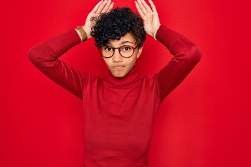 Fototapeta na wymiar Young beautiful african american afro woman wearing turtleneck sweater and glasses Doing bunny ears gesture with hands palms looking cynical and skeptical. Easter rabbit concept.