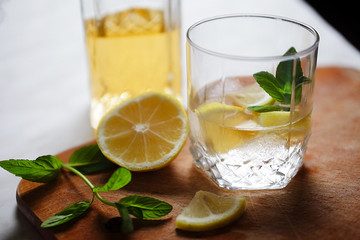 rum with ice lemon and mint stands on a light table, soft focus