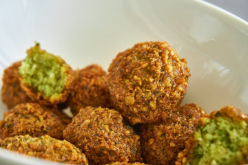 Close-up of fresh and crispy falafels balls inside a white bowl, authentic deep fried chickpea hot round falafels