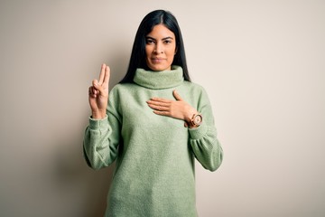Young beautiful hispanic woman wearing green winter sweater over isolated background smiling...