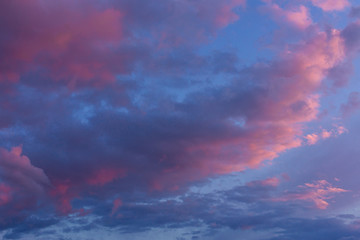 Naklejka na ściany i meble Cloudy sunset sky. Lilac light on a blue cloudy sky.