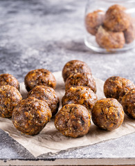 Fruit and nut energy balls on parchment paper on gray background.