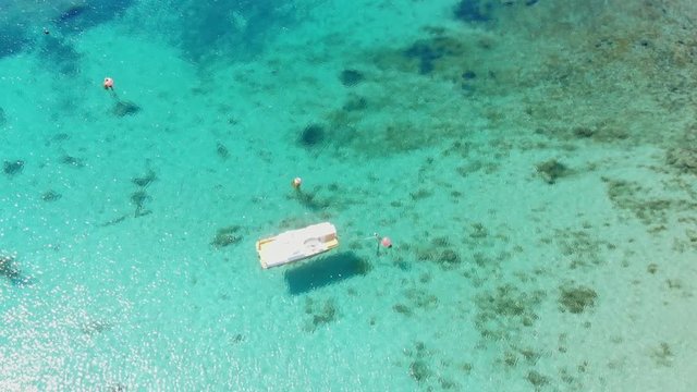 Overflight small boat with shadow projected on transparent seabed with sand rocks and poseidonia