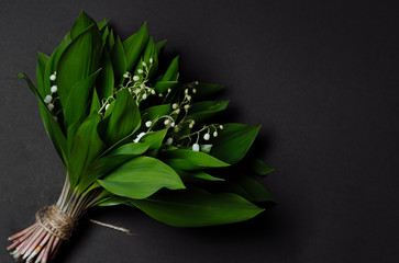 
Bouquet of lilies of the valley on a black background backdrop. Copy space