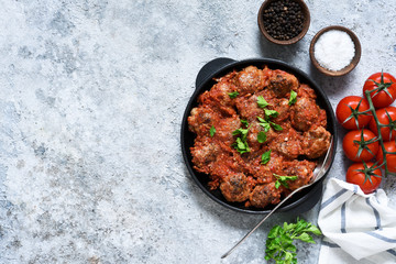 Frying pan with meat balls with tomato sauce on a concrete background.