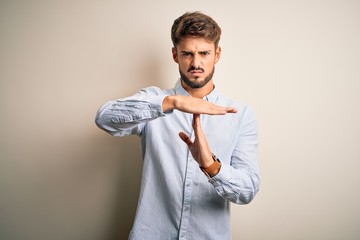 Young handsome man with beard wearing striped shirt standing over white background Doing time out...