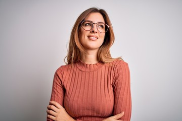 Obraz premium Young beautiful brunette woman wearing casual sweater and glasses over white background looking away to side with smile on face, natural expression. Laughing confident.