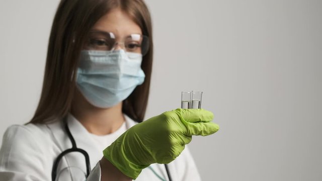 Girl doctor in a mask and gloves holds test tubes. Health, medical