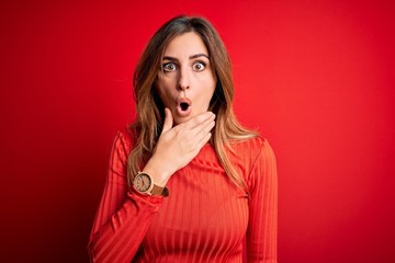 Young beautiful brunette woman wearing casual turtleneck sweater over red background Looking fascinated with disbelief, surprise and amazed expression with hands on chin