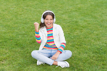 Happiness is not something you sit back and wait. Listen music while relaxing outdoor. Kid girl enjoy music green grass meadow. Child headphones listen music. Cool girl headphones listening music