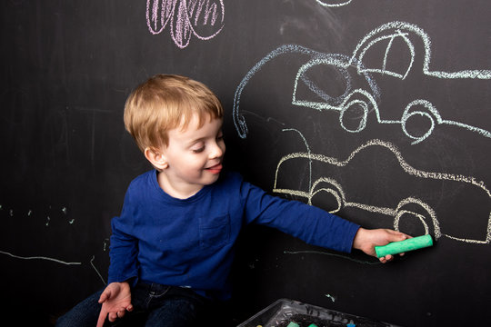 a three year old child draws in chalk on a slate wall of a typewriter. Close-up of European appearance. home leisure.