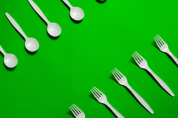 eco-friendly disposable tableware on a green background. isolate. corn starch spoons and forks. biodegradable dishes. natural materials for replacing plastic. place for text