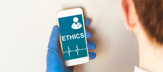 Hand in medical glove holding smartphone on white background. Blank screen with ETHICS text.