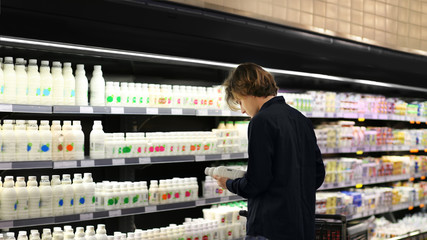 Teenager shopping in supermarket, reading product information	
