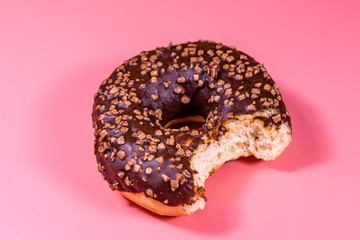 Bitten donut with chocolate glaze on top isolated on a pink background