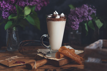 Caffe latte on dark moody background with flowers. - 347974132