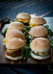 Closeup of fresh burgers with molten cheese on a wooden plate
