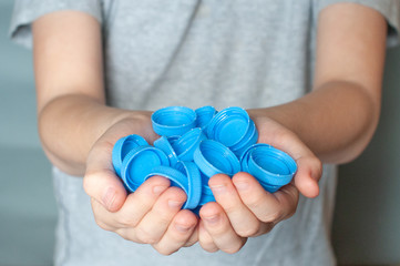 hand holding plastic caps for recycling to save the environment, on a white background, copy spase.