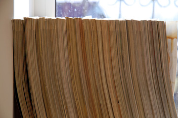 old news magazines are standing on a shelf opposite the window
