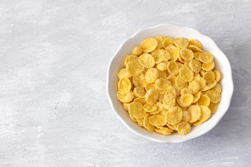 Sweet crunchy cornflakes on a gray textured background. Fast tasty breakfast, top view, free space, horizontal