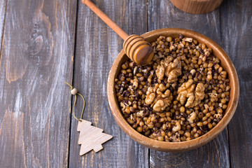 Sochivo, kutya - traditional Slavic holiday ritual dish (Russian, Ukrainian, Belarusian) of whole wheat, poppy, walnuts and honey in wooden bowl on wooden table	
