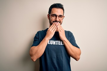 Handsome man with beard wearing t-shirt with volunteer message over white background laughing and...