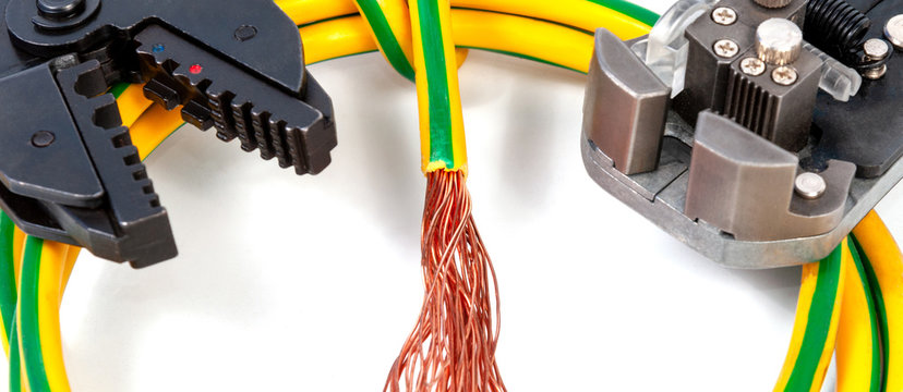 Electrician's tools. Stripper for stripping insulation on a wires and crimper for crimping lugs with grounding cable on a white background, close-up