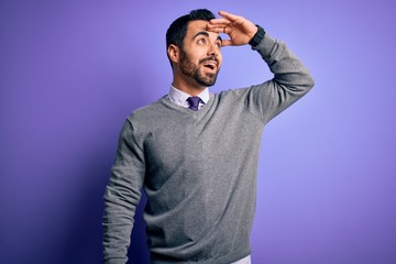 Handsome businessman with beard wearing casual tie standing over purple background very happy and smiling looking far away with hand over head. Searching concept.