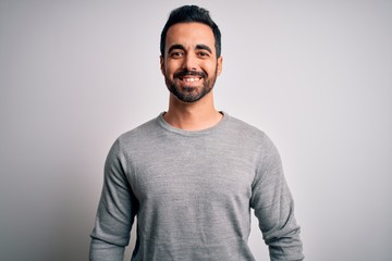 Young handsome man with beard wearing casual sweater standing over white background with a happy and cool smile on face. Lucky person.