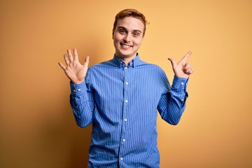 Young handsome redhead man wearing casual striped shirt over isolated yellow background showing and pointing up with fingers number seven while smiling confident and happy.