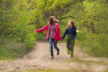 happy girl and boy run along the forest road