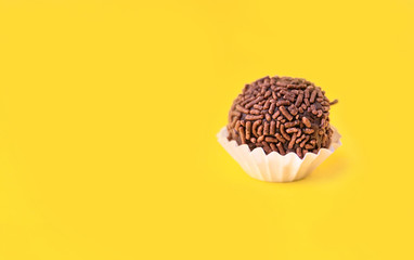 Brigadeiro (Brigadier) a Brazilian chocolate candy. Traditional Brazilian handmade chocolate sweet. Isolated on yellow background. 