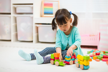 toddler girl playing creative toy blocks at home against white background