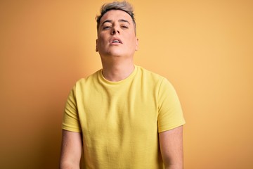 Fototapeta premium Young handsome modern man wearing yellow shirt over yellow isolated background Relaxed with serious expression on face. Simple and natural looking at the camera.