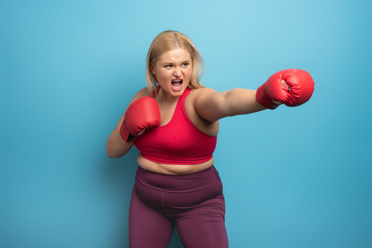 Fat Girl In Fitness Suite Does Boxing. Cyan Background