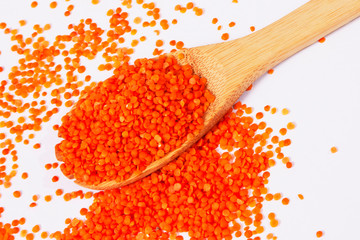 Red lentils with wooden spoon on white background