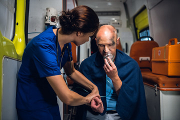 A female doctor checking her patient's pulse and talking to him to comfort him