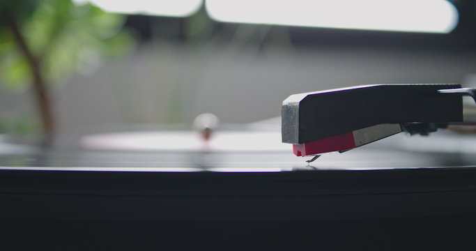 Closeup view of vintage headshell of portable record player strart playing on vynil record on blurred background