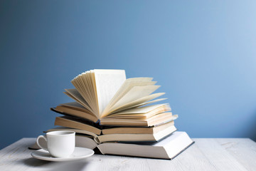 open book and cup of coffee on a background of a blue wall. Concept - online learning.