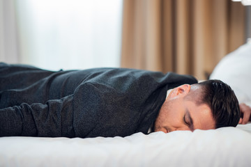 Close-up of a young man in suit sleeping on a bed