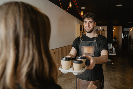 barista camarero entregando un pedido de caf&eacute;s para llevar a una mujer en un coffee shop