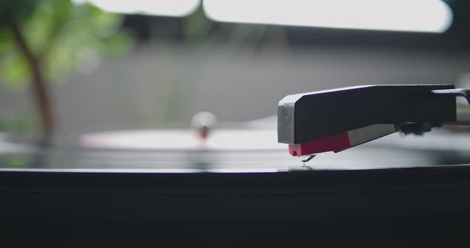 Closeup view of vintage headshell of portable record player strart playing on vynil record on blurred background